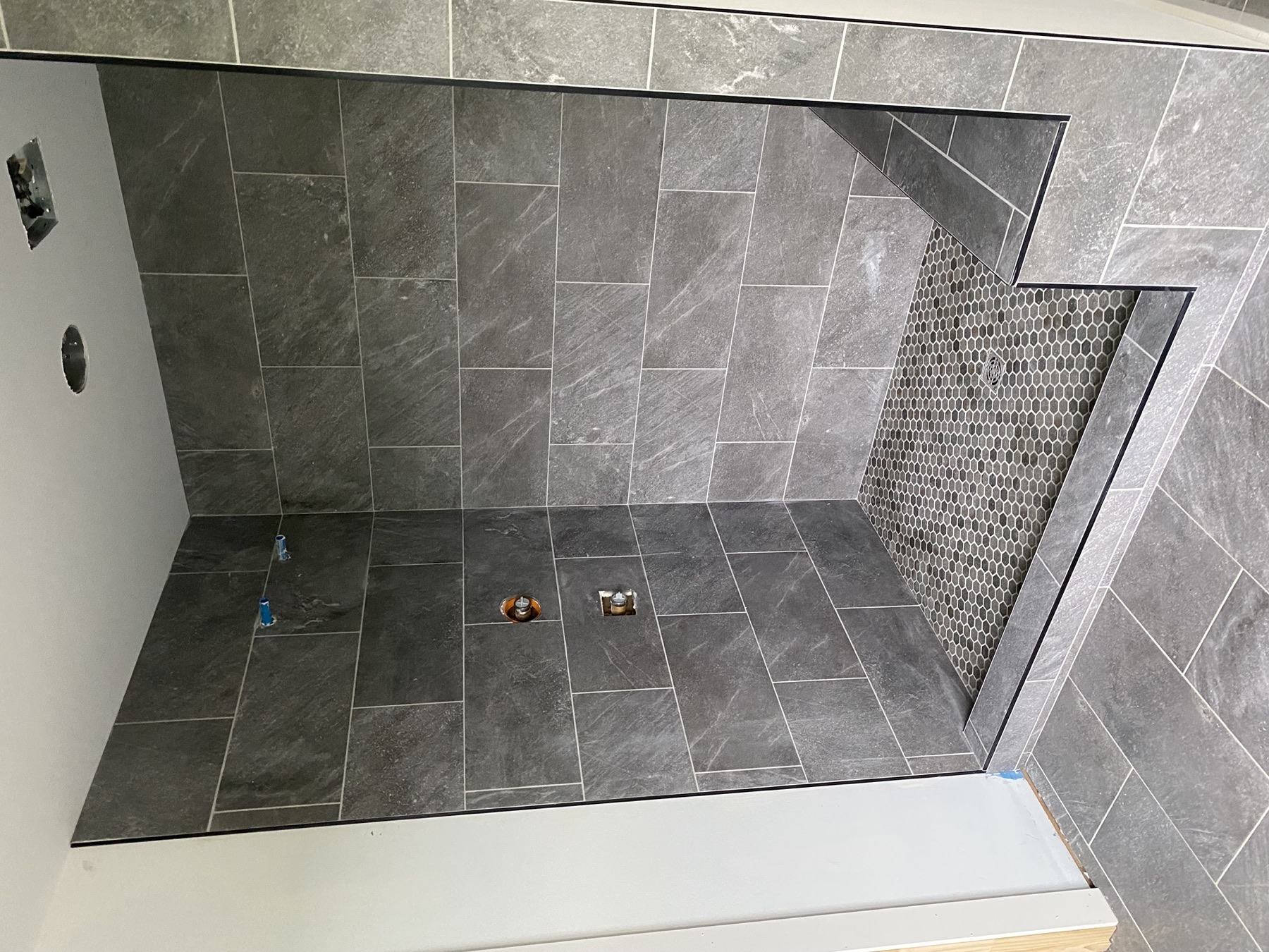 Charcoal walk-in shower with hex mosaic floor, bench, and matching floor tile